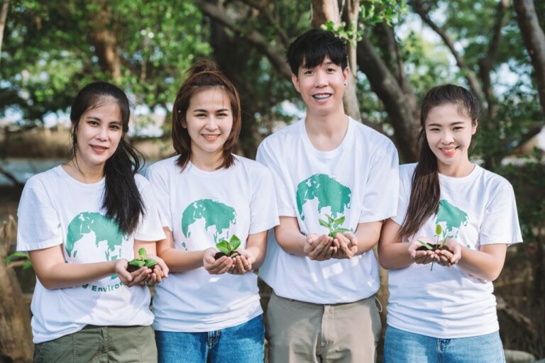 Volunteer people teamwork holding small plants seedling for growing in forest